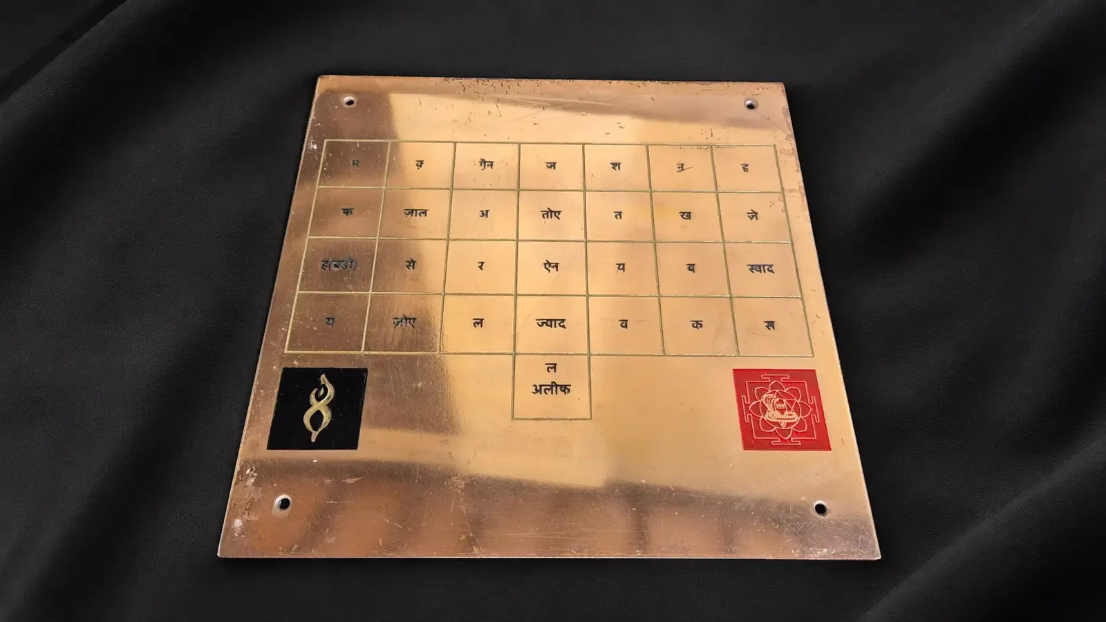 Copper plaque engraved with a Yantra on black fabric